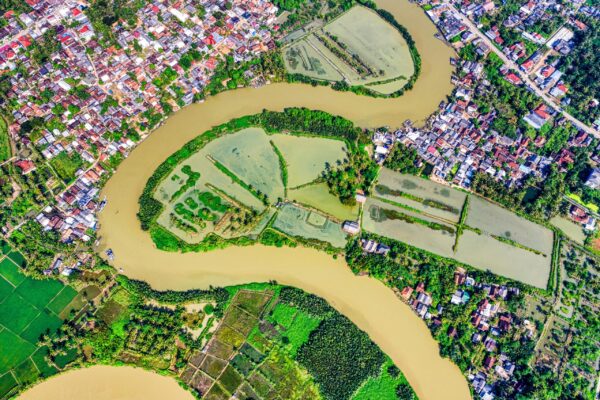 Vibrant aerial view of a river bending through lush farmland and a rural town.
